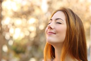 Portrait of a beautiful woman doing breath exercises with an autumn unfocused background